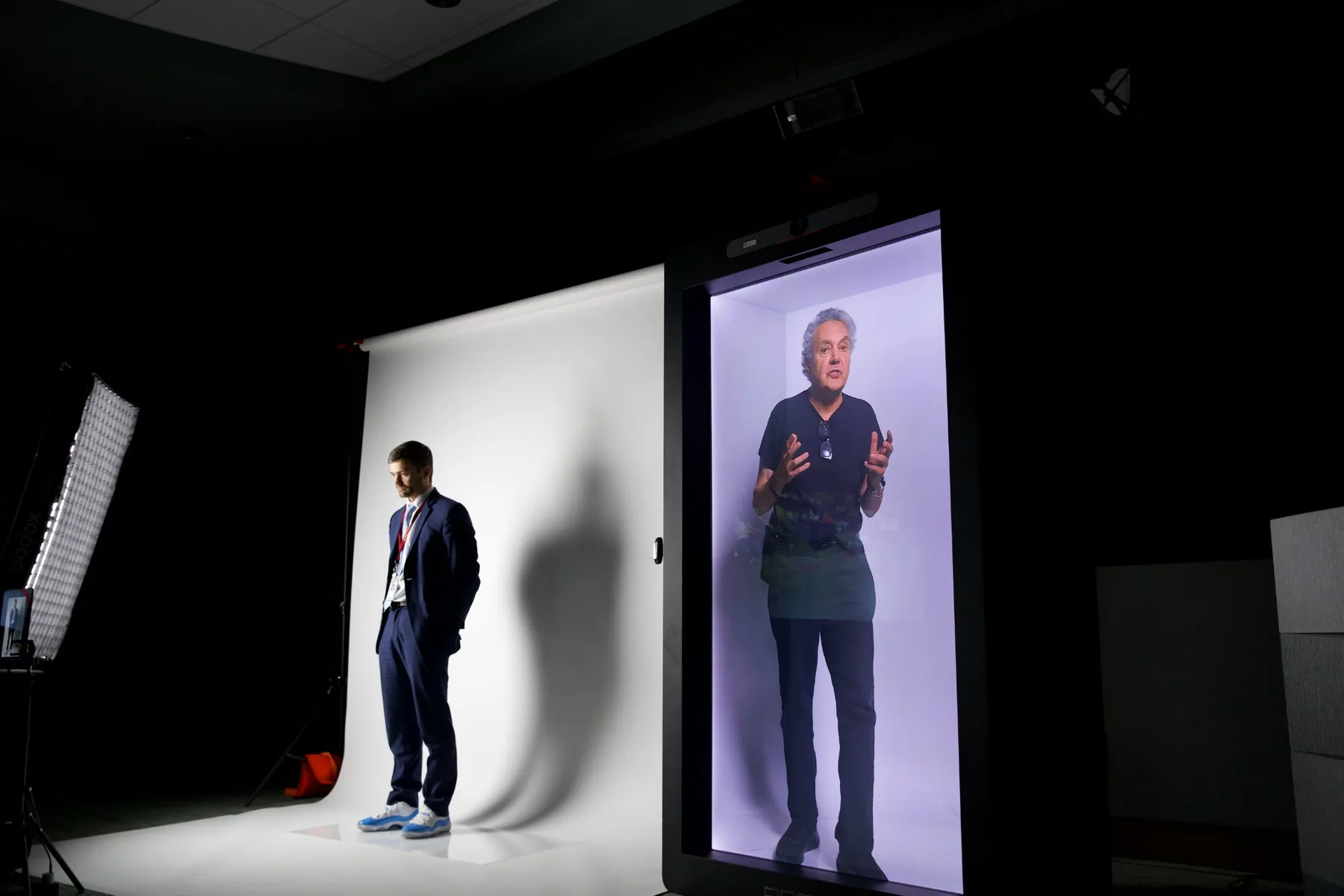 Michael Hollins beside a life-size holographic presenter during a Digital Hollywood holoSTAGE panel presentation in July 2026