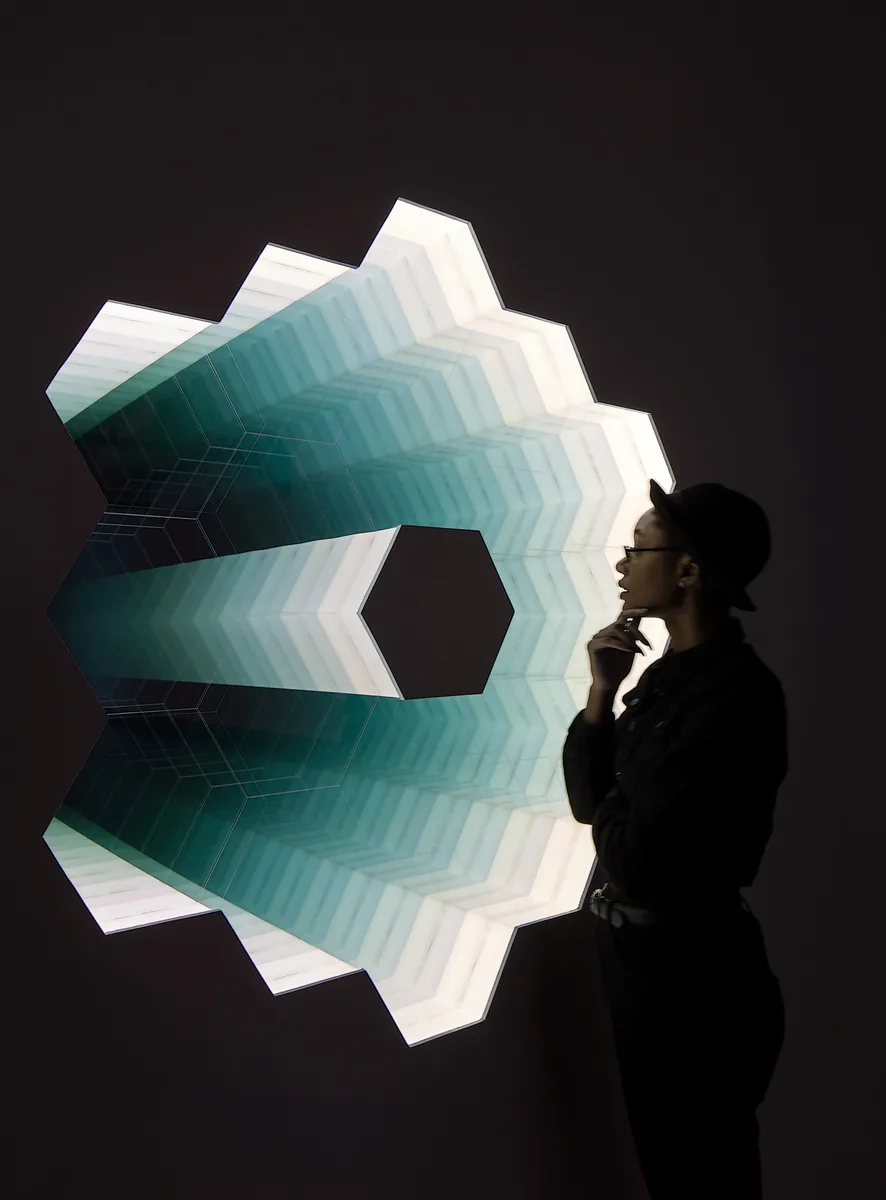 Visitor examining an illuminated work by Adam Belt in the Light exhibition at KANEKO in 2018